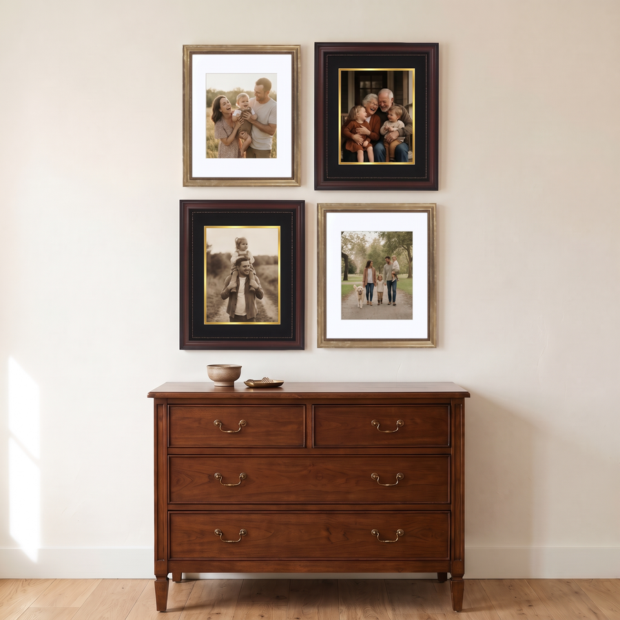 Mahogany & Gold Quad: four 11x14 frames alternating gold Heirloom and mahogany Legacy, in a two-by-two grid. Shown in a study, above a traditional wooden chest of drawers, with family photos in the frames 
