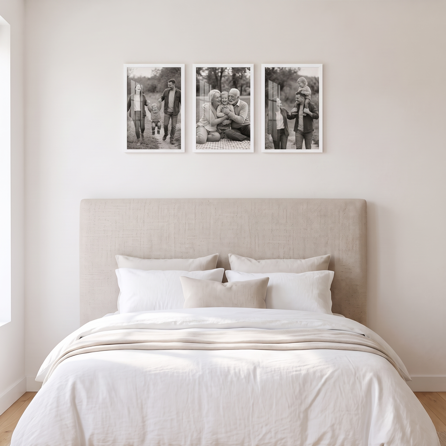 Signature White Trio: three identical unmatted white Signature 12x18 frames in one even row. Shown in a bright bedroom, above a bed with a linen upholstered headboard and white bedding, with family photos in the frames 