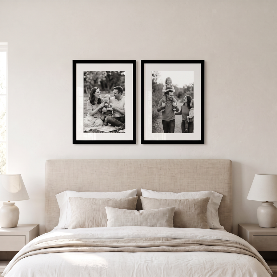 Epic Matted Pair: two black Epic 16x22 frames matted to 12x18, hung side by side. Shown in a calm bedroom, above a bed with an oatmeal linen headboard, with family photos in the frames 