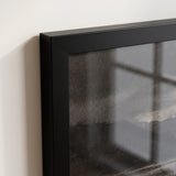 Close-up of the polished black poster-frame corner with plexiglass front, the print meeting the moulding directly 